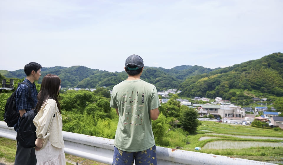 [写真] 棚田を見渡しながらガイドの説明を聞く様子