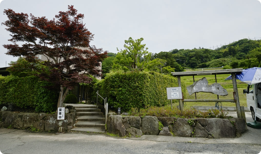 [写真] 緑に囲まれた入口と案内看板