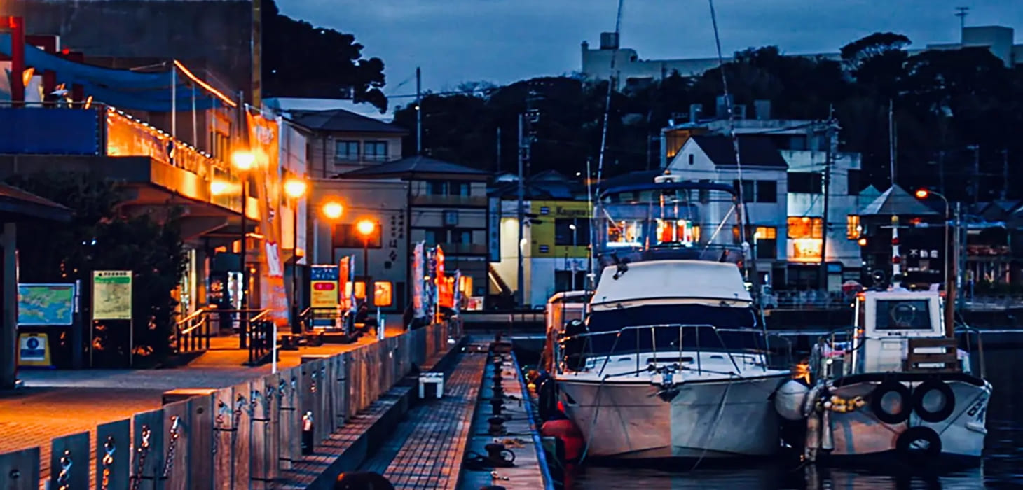 [写真] 夕暮れ時、街灯が優しく灯る情緒あふれる港に停泊する船