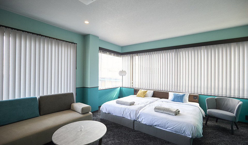 [写真] 水色を基調としたモダンで広々としたホテルの客室