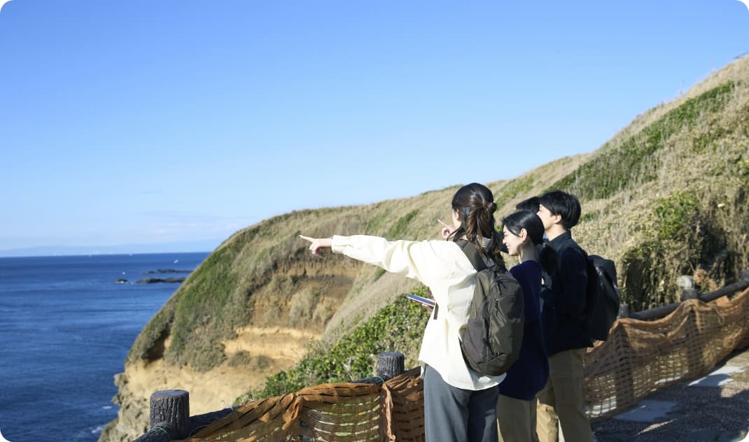 [写真] 展望スポットから海を指差し、景色を楽しむ様子