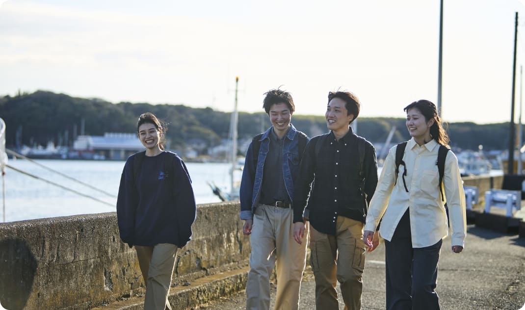 [写真] 柔らかな光が差し込む港沿いを、笑顔で散策する様子