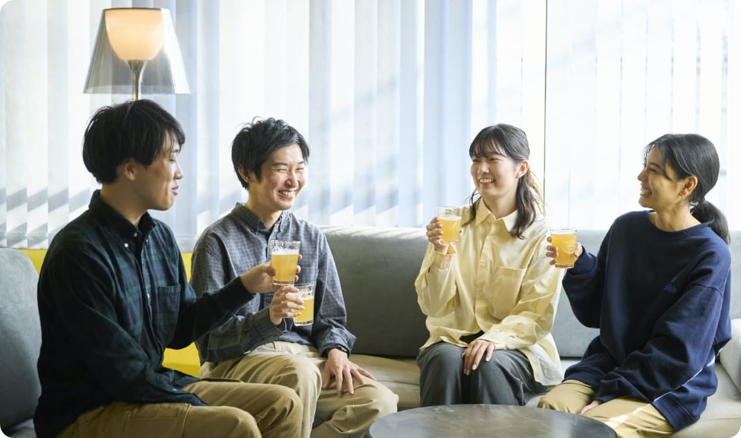 [写真] 明るいリビングのソファに座り、ビールを片手にリラックスする様子