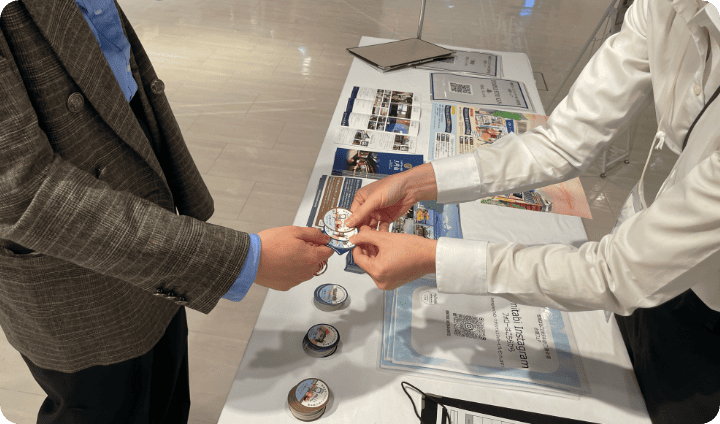 [写真] ブースでバッジを受け取る来場者