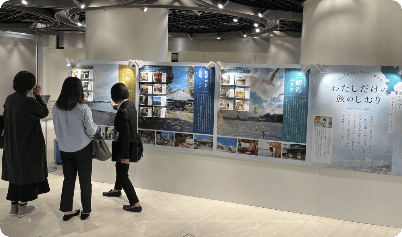 [写真] 地域紹介の大きなパネルを見る来場者たち