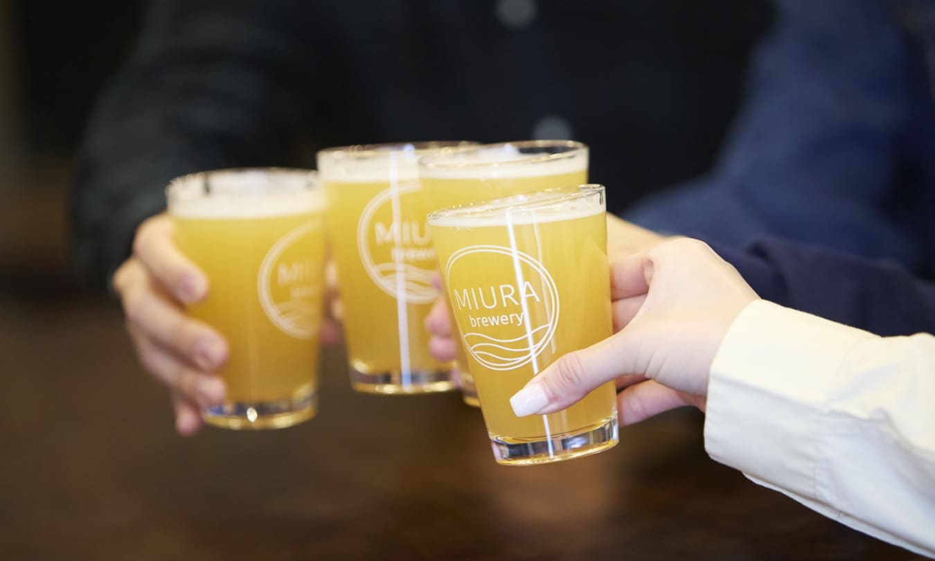 [写真] 「MIURA brewery」のロゴ入りグラスを掲げて乾杯する様子